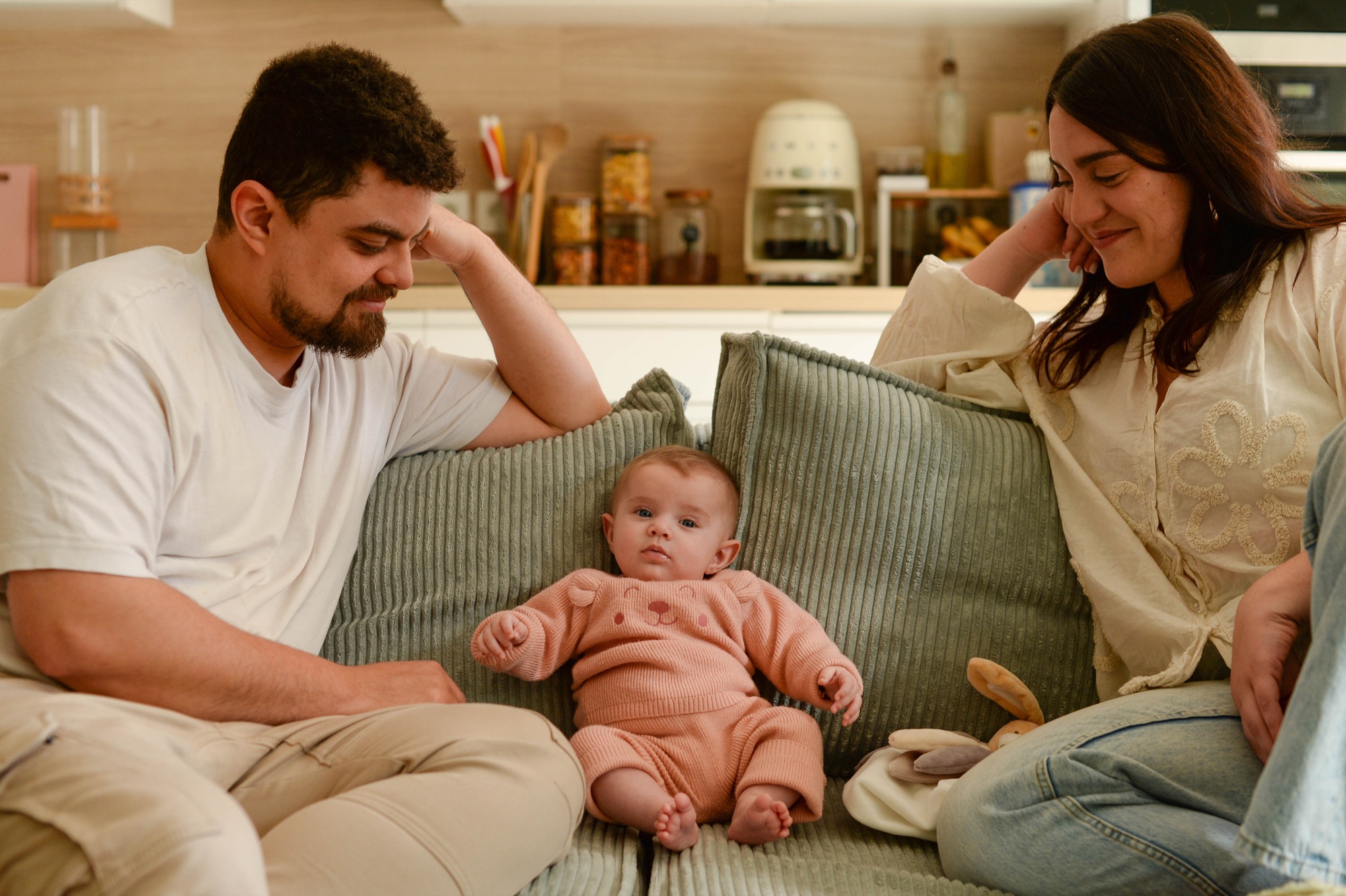 Jeunes parents avec leur bébé sur un canapé vert
