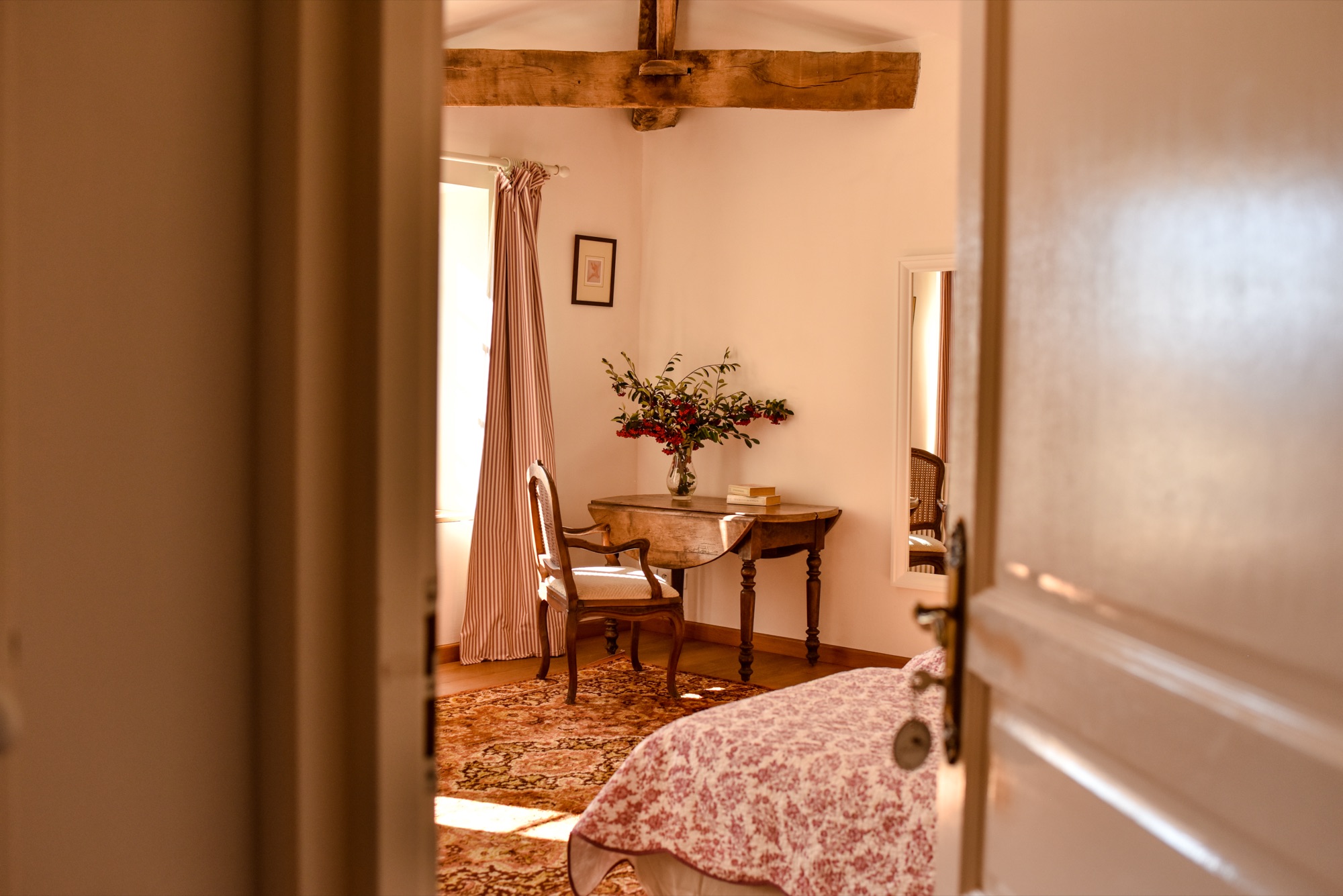 Chambre avec poutres apparentes et bouquet de fleurs rouges